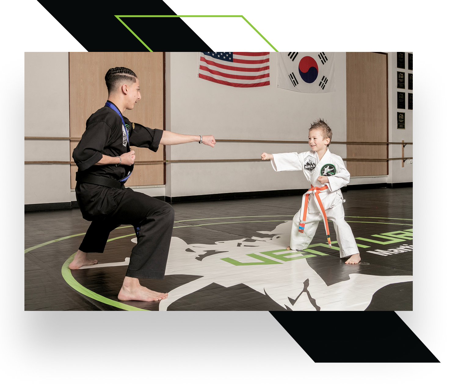 Two martial artists in a training pose, one adult in black attire and a child in a white uniform with an orange belt.
