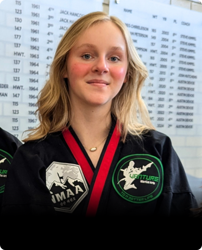 Martial artist in uniform smiling at a training facility.