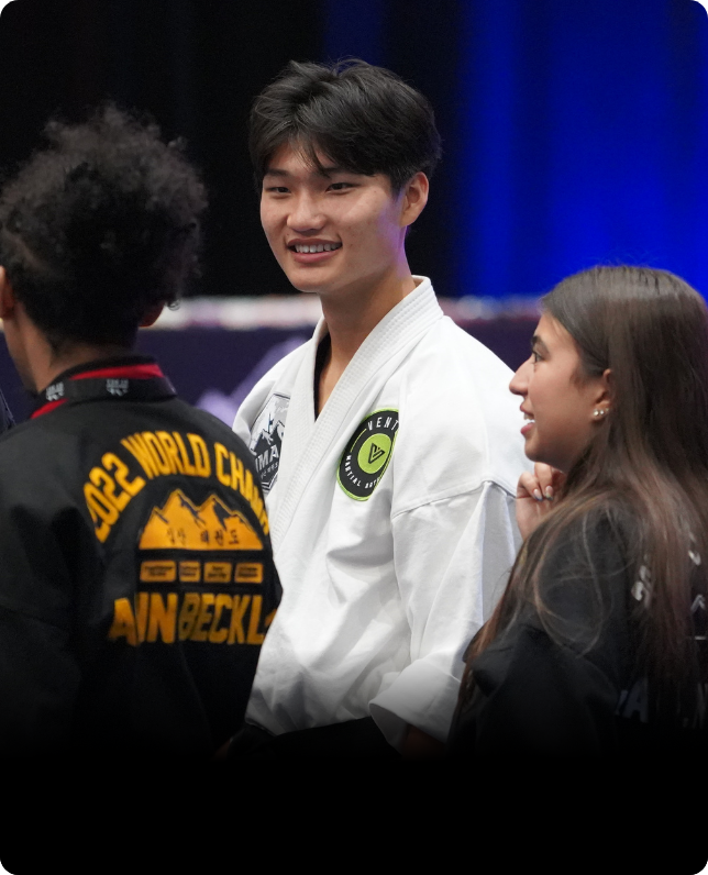 Young martial artist smiles while chatting with friends at event.