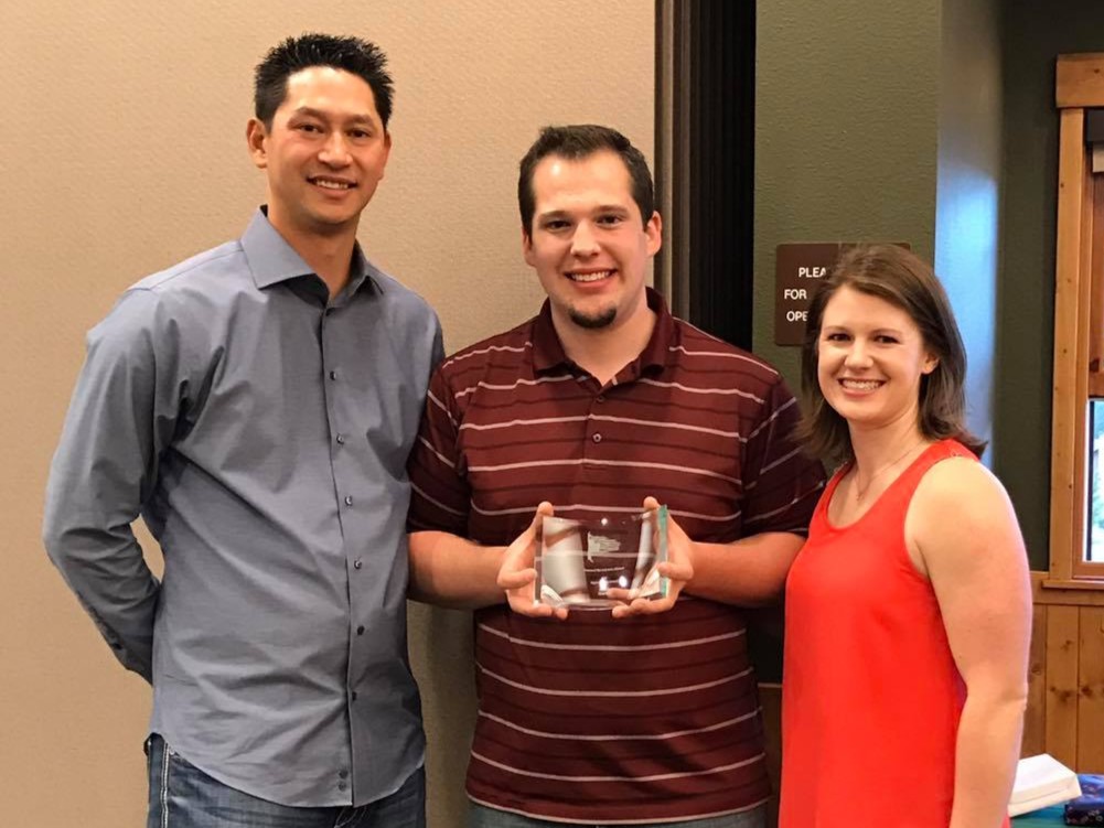 Award presentation with three people smiling together.