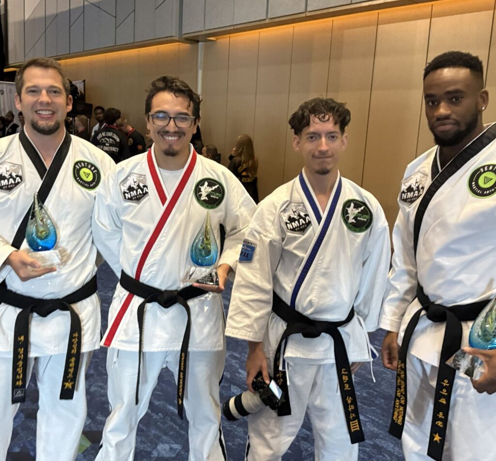 Martial arts programs award winners holding trophies at an event.